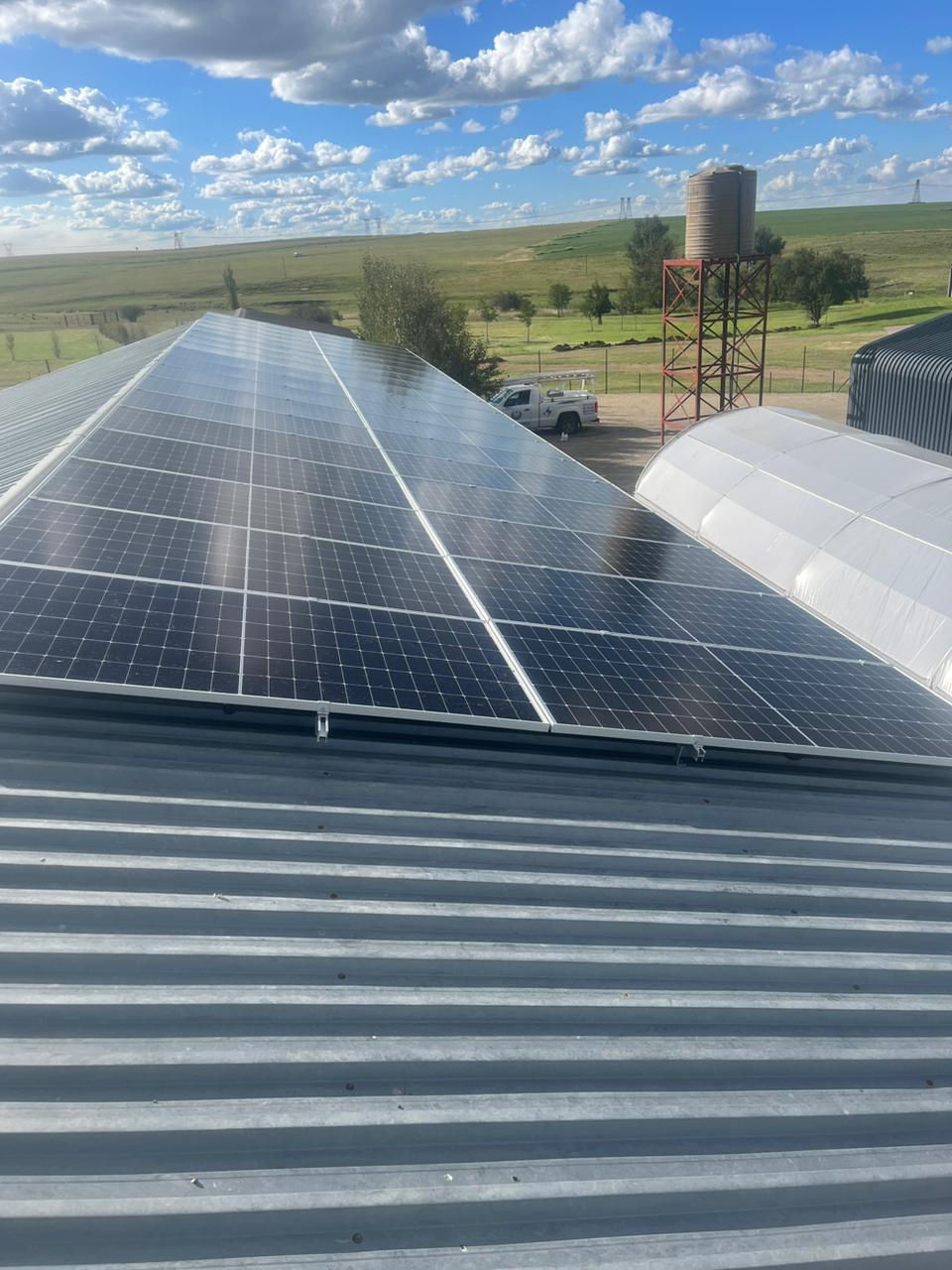 Large rooftop solar panel installation overlooking open farmland